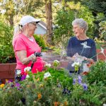 Someren Glen Senior Living Community in Centennial, CO - older woman watering garden bed and talking to friend square